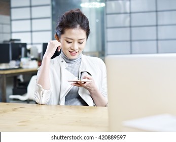 young asian office woman looking at cellphone and smiling.