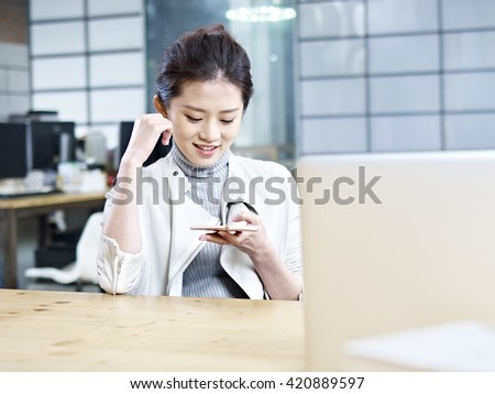 young asian office woman looking at cellphone and smiling.