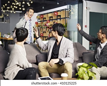 young asian office worker saying good-bye to colleagues in office before going home.