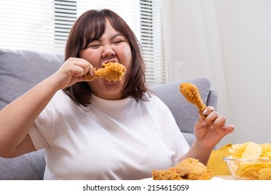 Young Asian Oversize Women Gain Weight While Eating Fried Chicken, Potato Chips And French Fried. Junk Food That Can Cause Obesity And Unhealthy For Human Body.