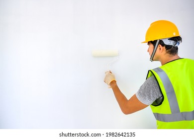 Young Asian Painter Happy Painting The Walls Inside The White House With A Paint Roller In A New House. Idea: Home Decor