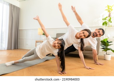 Young  Asian Parents With Child Meditating At Home Isolated In Room.  Family, Sport, Yoga Concept.