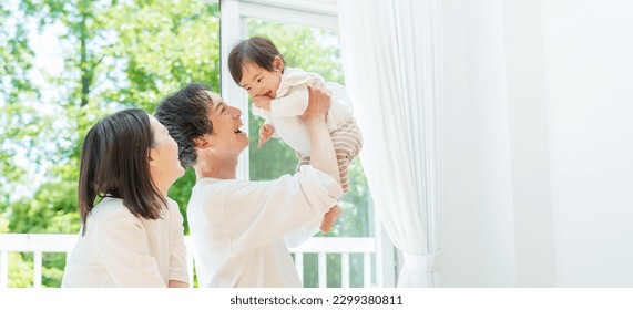 young asian parents lifting and playing with their baby in the bedroom - Powered by Shutterstock