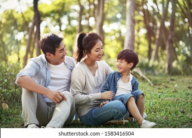 Young Asian Parents And Son Having Fun Outdoors In Park