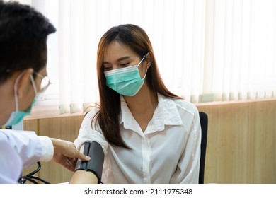 Young Asian Patient Wearing Surgical Face Mask While Visit A Doctor And Use Sphygmomanometer To Measure Blood Pressure For Annual Medical Check Up. 
