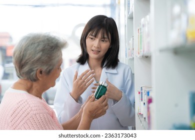 Young Asian pharmacist talking with customer at pharmacy counter. She tells customers about drug information at the pharmacy. - Powered by Shutterstock