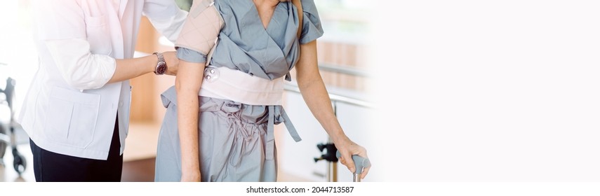 Young Asian Physical Therapist Working With Senior Woman On Walking With A Walker