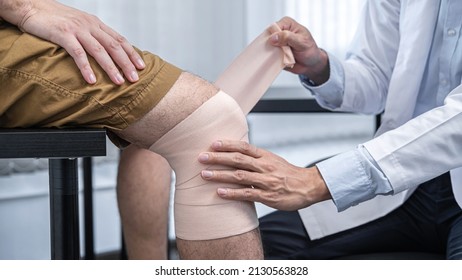 Fisioterapeuta asiática joven rodilla de vendaje de pacientes humanos con lesión durante el tratamiento de curación y para dar terapias de rehabilitación en la clínica