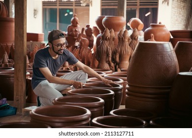 young asian pottery craftsman holding pottery products ready for sale