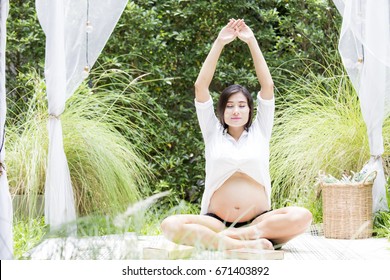 Young Asian Pregnant Woman Doing Yoga And Showing Her Belly At Outdoor Place, 20-30 Years Old.