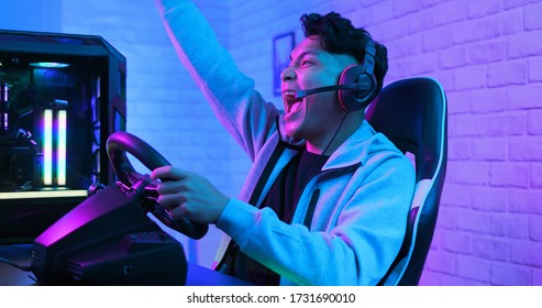 Young Asian Pro Gamer Man Win Car Racing Online Video Game and Cheer Up with Fist Gesture