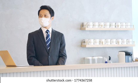 Young Asian Receptionist Talking With Customers With Surgical Mask. Hotel Worker. Store Clerk.