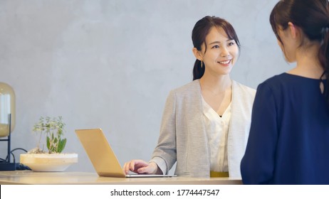 Young Asian Receptionist Talking With Customers. Hotel Worker. Store Clerk.