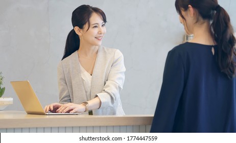 Young Asian Receptionist Talking With Customers. Hotel Worker. Store Clerk.