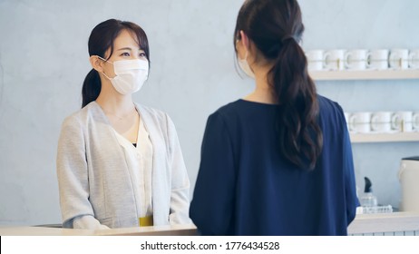 Young Asian Receptionist Talking With Customers With Surgical Mask. Hotel Worker. Store Clerk.