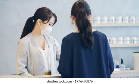 Young Asian Receptionist Talking With Customers With Surgical Mask. Hotel Worker. Store Clerk.