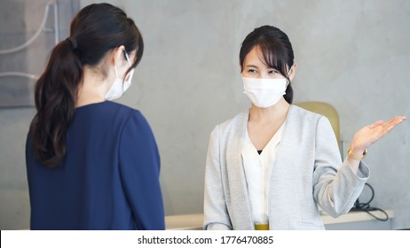 Young Asian Receptionist Talking With Customers With Surgical Mask. Hotel Worker. Store Clerk.