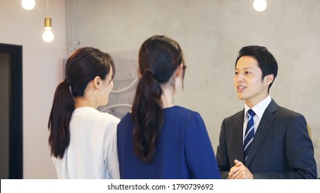 Young Asian Receptionist Talking With Customers. Hotel Worker. Store Clerk.