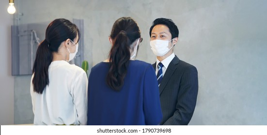 Young Asian Receptionist Talking With Customers With Surgical Mask. Hotel Worker. Store Clerk.