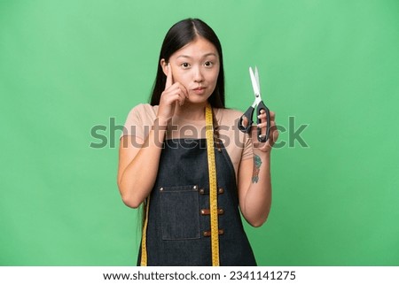 Young Asian seamstress woman over isolated background thinking an idea