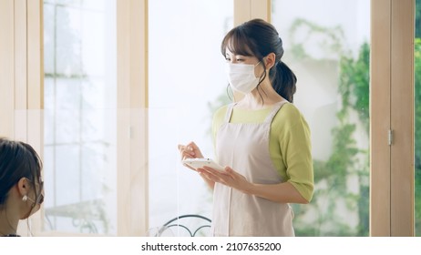 Young Asian Shop Clerk With Facial Mask Working In The Cafe.