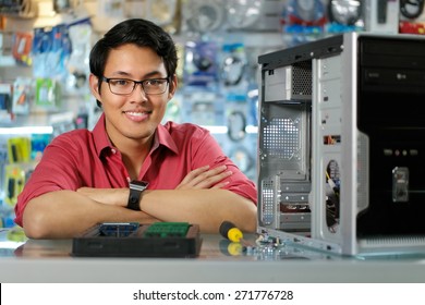 Young Asian Shop Owner Working In Computer Store, Repairing Computer And Adding Ram To Pc. Portrait Of Man Smiling At Camera