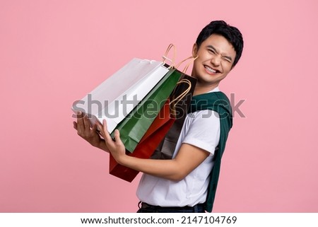 Young Asian shopper carrying a lot of shopping bags.