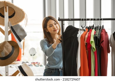 Young Asian shopping woman choosing and buying cloths in the clothing store. - Powered by Shutterstock