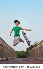 Young Asian Skateboarder Jumping In The Air In Joy