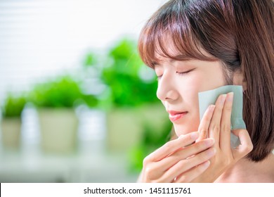 Young asian skin care woman smile and use oil blotting paper on her face