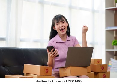 Young Asian Small Business Owner Successful Selling Online And Holding Smartphone With Laptop Computer. Happy Asian Business Woman Successful Excited Raised Hands Rejoicing.