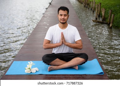 Young Asian smile handsome man, 20-30 years old, Doing Yoga meditation exercise by lotus pose on wooden bridge above peaceful lakes. Healthcare and Fitness concept - Powered by Shutterstock