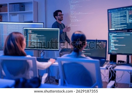 young Asian software development manager leads a late-night office discussion with his executive team, mentoring developers and analyzing source code to guide programming and project development