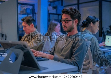 young Asian software development manager leads a late-night office discussion with his executive team, mentoring developers and analyzing source code to guide programming and project development