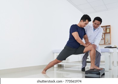 Young Asian Sportsman Doing Exercise Under Control Of Physiotherapist