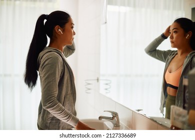 Young Asian Sportswoman Standing In Front Of A Mirror In Public Bathroom At The Gym.