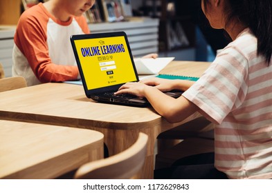 Young Asian Student Log In To Website Online Learning Center At Table In Library In School.digital Age Education Concept