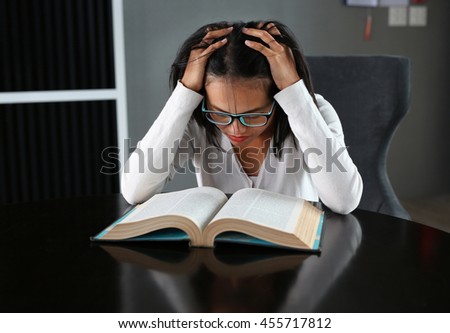 Young asian student reading a book under mental pressure