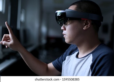 Young asian student trying Mixed reality with VR glasses in the laboratory. Gesture of men when using Virtual Reality headset