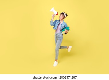 Young Asian student woman shouting into megaphone making announcement in isolated on yellow background.