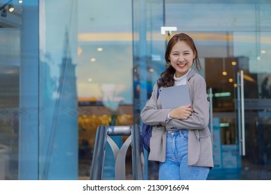 Young Asian Students Hold Tablets And Sling Bags In Front Of A Shopping Mall. Them In Public
