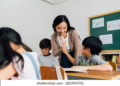 Young Asian teacher giving boy high five in school, success, achievement, happiness. Asia school boy with young woman in class.