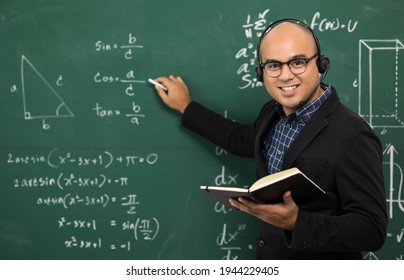 Young Asian Teacher Man Teaching Video Conference With Student. Male Indian Teacher Training The Mathematics In Classroom From Online Course. He Wearing Small Talk Headset.