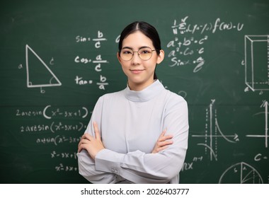 Young asian teacher woman teaching standing with arms crossed video conference with student. Female teacher training the mathematics in classroom blackboard from online course.