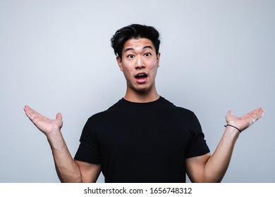 Young Asian Teen Standing Over Isolated Grey Background Holding Both Hands Up Copy Space For Product Placement With Surprise Expression