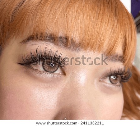Young Asian teenage girl doing fashionable orange hairstyle Both beautiful and cute like dolls. Currently receiving eyelash extension services by a beauty expert in the salon. or beauty salon