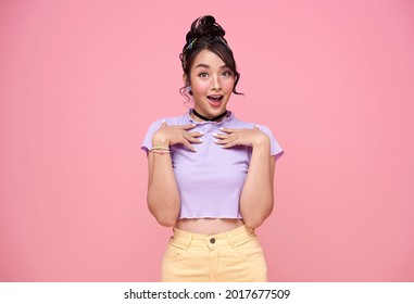 Young Asian teenage girl surprised excited isolated on pink background.	