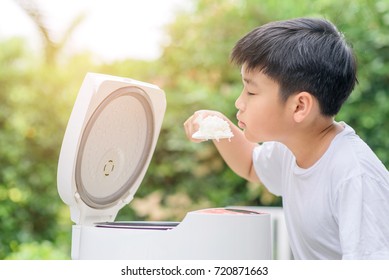 Young Asian Thai Boy And Electric Rice Cooker That Cooking A Very Good Smell Jasmine Rice Variety At Home Garden.