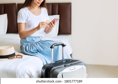 Young Asian Traveler In White T- Shirt Relaxing And Using Smartphone In Hotel Room After Check In. Travel Concept