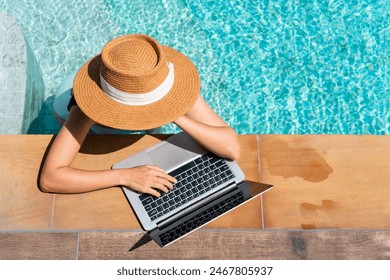 Young Asian traveler woman working on computer at pool in luxury resort during her summer holiday. Work from anywhere, Technology and lifestyle concept, copy space - Powered by Shutterstock